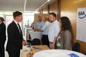 Sebastian Hartmann steht am Infostand der EAA und spricht mit zwei Fachberatenden